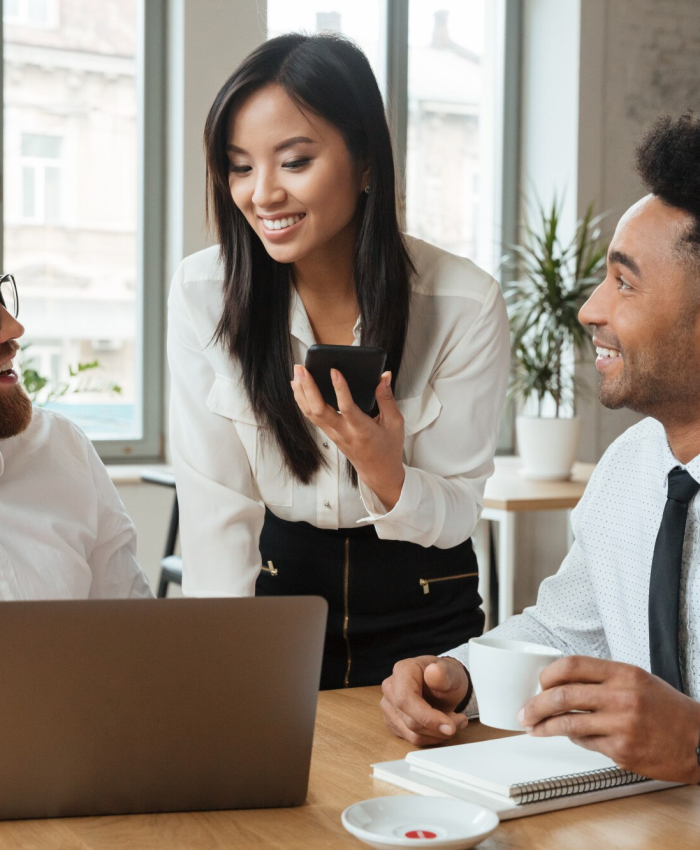 Staff members smiling and discussing business strategies in a bright office setting.